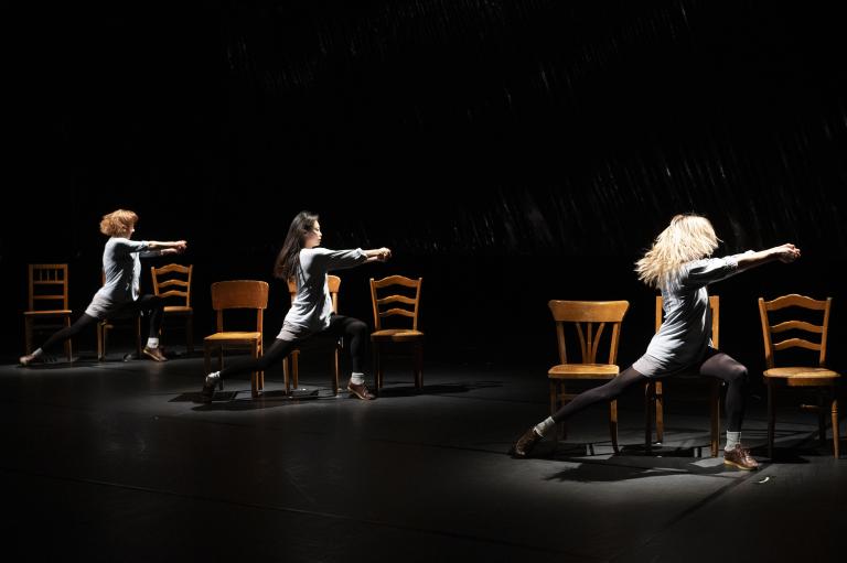 3 danseuses visibles dansant sur des chaises en bois